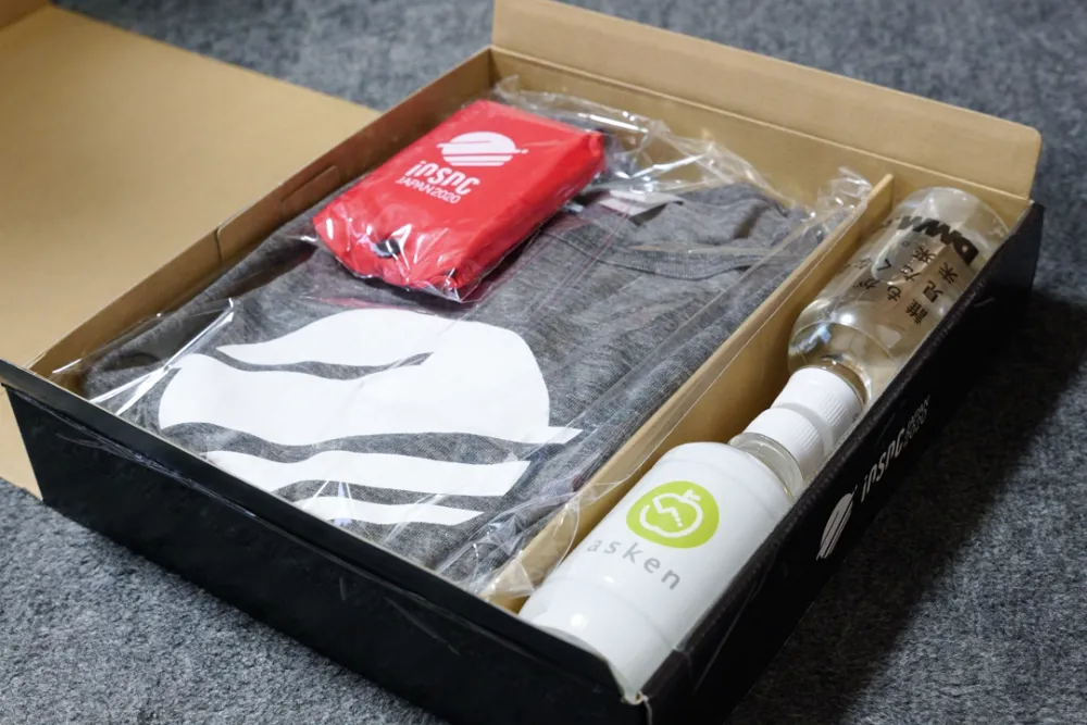 ノベルティボックスを開けたところ。簡単な作りのマイバッグやiOSDC Tシャツ、2本もあるボトルウォーターが見えてる。